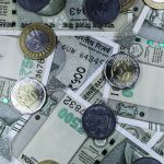 Notas de rupia indiana e moedas dispostas sobre uma superfície, representando o mercado financeiro do país