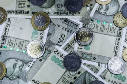 Notas de rupia indiana e moedas dispostas sobre uma superfície, representando o mercado financeiro do país