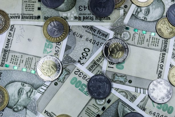 Notas de rupia indiana e moedas dispostas sobre uma superfície, representando o mercado financeiro do país