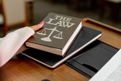 Livro com a inscrição “The Law” ao lado de uma balança da justiça sobre uma mesa de madeira.