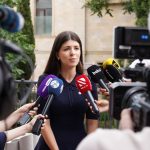 Profissional concede entrevista a jornalistas cercado por microfones durante uma cobertura de imprensa