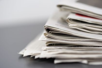 Jornais empilhados sobre uma mesa, representando a imprensa e o jornalismo.