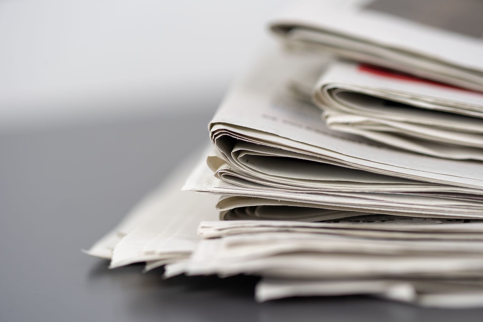 Jornais empilhados sobre uma mesa, representando a imprensa e o jornalismo.