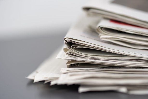 Jornais empilhados sobre uma mesa, representando a imprensa escrita e o trabalho editorial.