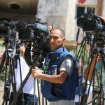 Jornalistas fazem uma transmissão ao vivo ao ar livre na Faixa de Gaza.