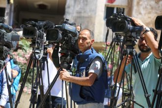Jornalistas fazem uma transmissão ao vivo ao ar livre na Faixa de Gaza.
