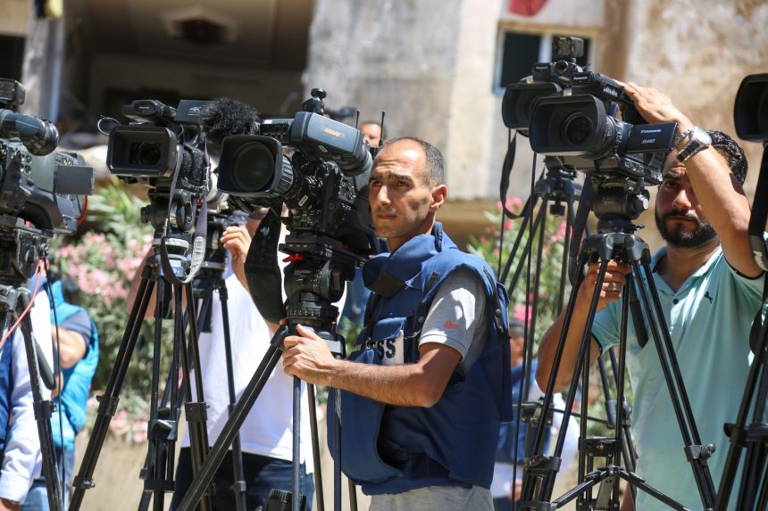 Jornalistas fazem uma transmissão ao vivo ao ar livre na Faixa de Gaza.