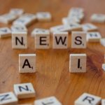 Peças de madeira formam as palavras “AI” e “NEWS”, simbolizando a aplicação da inteligência artificial ao jornalismo.
