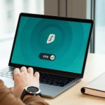 Pessoa usando um aplicativo de VPN em um laptop sobre a mesa de um escritório moderno