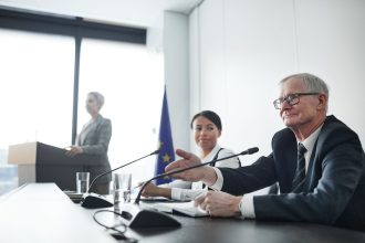 Painelistas participam de uma conferência internacional diante de uma plateia.
